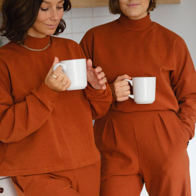 Two girls relaxing in the kitchen wearing their comfortable loungewear. Orange luxe fleece.